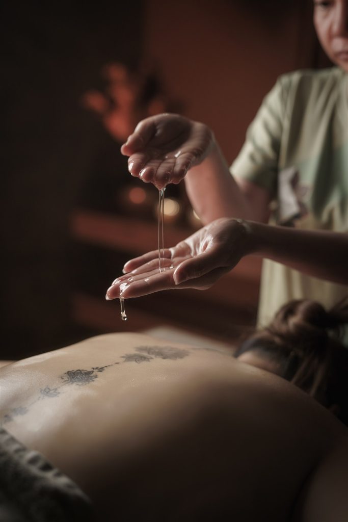 Massage oil dripping between a therapist’s hands